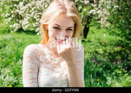 Allegro bionda nel giardino fiorito. Ragazza vestita abito bianco. Primo piano. Foto Stock