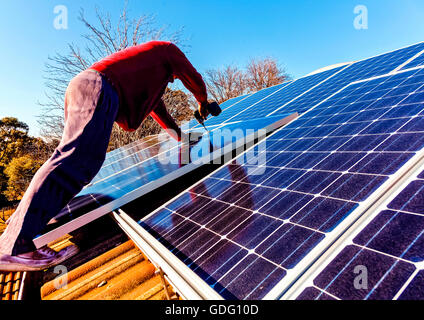 Workman di installare pannelli solari sul tetto della casa Foto Stock
