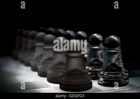 Scacchi di cristallo pezzi su una riga .su sfondo nero. Foto Stock