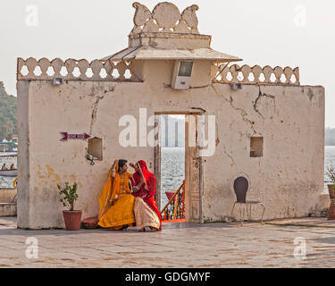 Due giovani donne Indù colorfull in sari attendere per un giro in barca sul lago a Udaipur, India Foto Stock