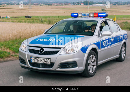 Polish auto della polizia passare rapidamente attraverso i campi di grano. Foto Stock