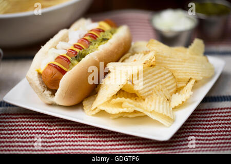Veggie hot dog e rabboccato con senape, ketchup, cipolle e assaporare, servita con patatine (chip). Foto Stock