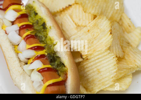 Veggie hot dog e rabboccato con senape, ketchup, cipolle e assaporare, servita con patatine (chip). Foto Stock