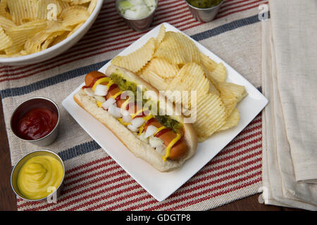 Veggie hot dog e rabboccato con senape, ketchup, cipolle e assaporare, servita con patatine (chip). Foto Stock