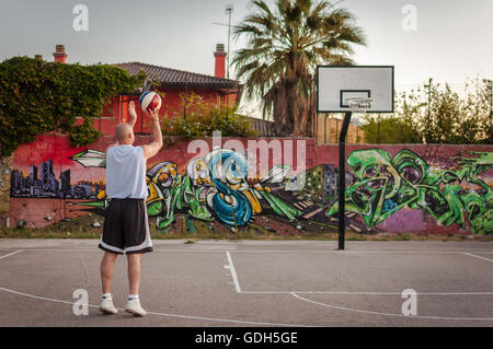 Giocatore di basket in città parco giochi al tramonto Foto Stock