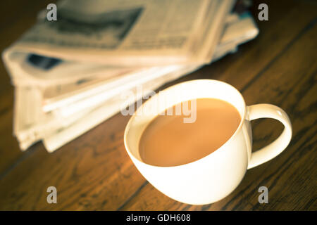 Tazza di caffè e un giornale con calde tonalità vintage Foto Stock