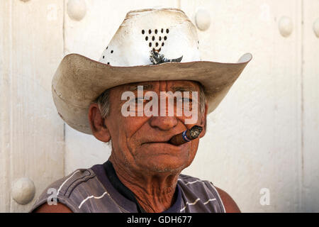 Il vecchio uomo cubano indossando cappello di paglia, fumare un sigaro, Trinidad, Cuba Foto Stock