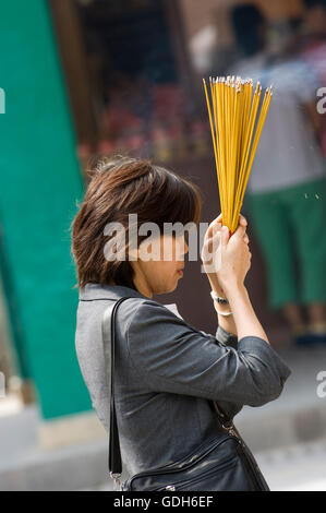 Donna che mantiene i bastoncini di incenso, Wong Tai Sin Temple, Wong Tai Sin district, Kowloon, Hong Kong, Cina, Asia Foto Stock