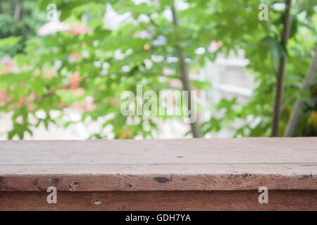 Svuotare tavolo in legno con blur foglie verdi sfondo bokeh di fondo Foto Stock