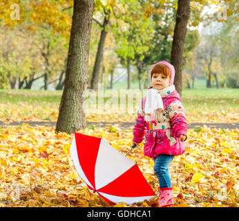 Una piccola ragazza camminare nel parco con un ombrello Foto Stock