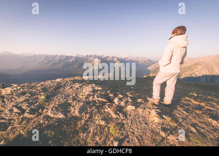 La donna guarda sunrise su valli e creste e picchi di montagna. Ampio angolo di visione da 3000 m in Valle d'Aosta. Annuncio di estate Foto Stock