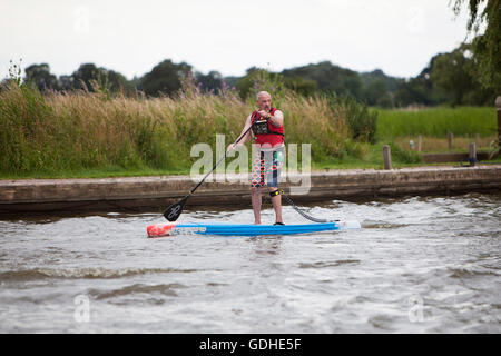 Norfolk Broads, UK. 16 Luglio, 2016. La sesta Norfolk Broads classica gara SUP. Dieci e cinque miglia di corsi tra collina come riserva naturale e Martham passando per le rovine di San Benets Abbey, Thurne Mulino a vento e basso sotto il ponte medievale a Potter Heigham, negoziare innumerevoli vacanze cruisers e yacht lungo la strada. Originario delle Hawaii come sport, stand up paddle boarding è uno del Regno Unito il nuovissimo sport acquatici e i Broads Classic, organizzato da martham barche, attrae il debuttante e agguerriti piloti da tutto il paese. Credito: Adrian Buck/Alamy Live News Foto Stock