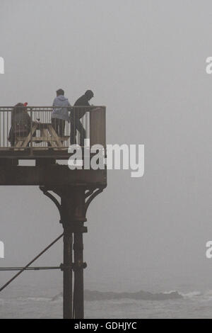 Aberystwyth Wales UK, domenica 17 luglio 2016 UK meteo: persone sul mare molo nella nebbia spessa grigio nebbia nuvoloso domenica Luglio 'Summer' pomeriggio . Il meteo Le previsioni per migliorare in modo significativo il martedì, con temperature meteo per volare a 28º centigradi Credito: Keith Morris / Alamy Live News Foto Stock