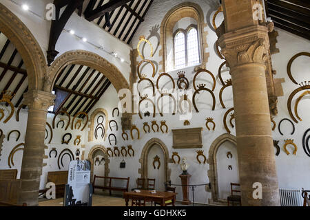 Interno della grande hall dove oltre 230 ferri di cavallo appesi alle pareti il castello di Oakham Rutland East Midlands UK Foto Stock