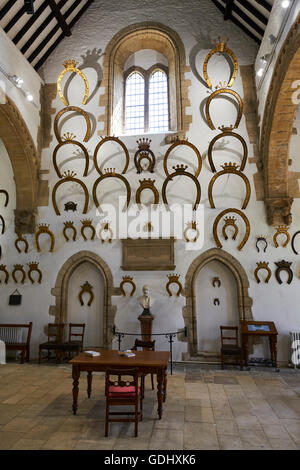 Interno della grande hall dove oltre 230 ferri di cavallo appesi alle pareti il castello di Oakham Rutland East Midlands UK Foto Stock