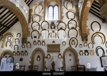 Interno della grande hall dove oltre 230 ferri di cavallo appesi alle pareti il castello di Oakham Rutland East Midlands UK Foto Stock