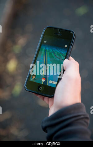 Adolescente utilizzando un iPhone per riprodurre la realtà aumentata gioco Pokemon Go Foto Stock