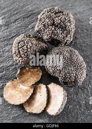 Tartufo nero e fettine di tartufo sulla scheda di grafite. Foto Stock