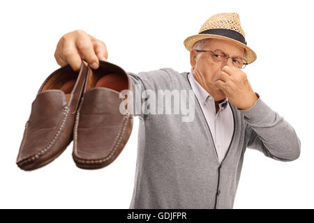 Disgustato senior tenendo un paio di scarpe stinky isolati su sfondo bianco Foto Stock