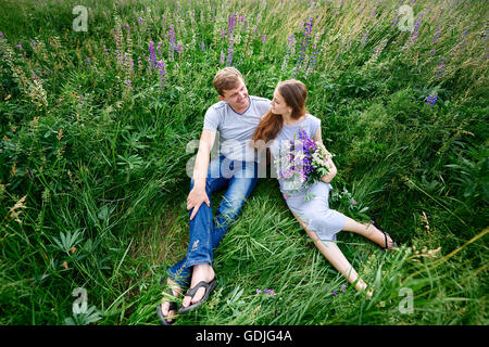 Matura in amore giacente in erba su un prato estivo Foto Stock