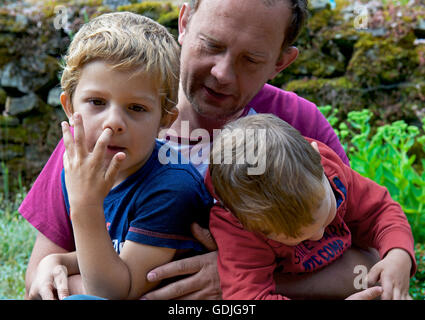 L uomo e i suoi due figli di età compresa tra due e cinque... uno di loro raccolta il suo naso Foto Stock