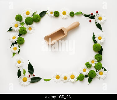 Cucchiaio di legno e lo spazio per il tuo testo o prodotto con decorazione di fiori di crisantemo e ficus foglie su sfondo bianco. 0 Foto Stock