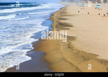 Un maschio solitario utilizzando un rivelatore di metallo lungo la linea di galleggiamento a Huntington Beach in California Foto Stock