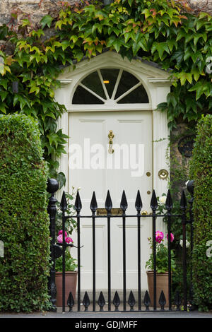 Helmsley, North Yorkshire - close-up di un bianco, verniciato, pannellata porta sotto una superficie radiale di ritaglio e dietro una cancellata in ferro battuto. Foto Stock