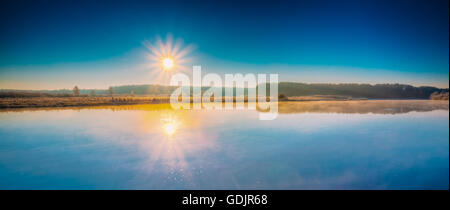 Panorama del tramonto sunrise sole sorge oltre il fiume. In autunno il gelo frozen river ricoperta di ghiaccio sottile. Foto Stock