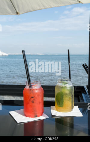 Due cocktail, fragola e la vodka e la calce e la vodka cocktails con il fiume sul retro Foto Stock