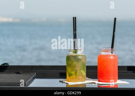 Due cocktail, fragola e la vodka e la calce e la vodka cocktails con il fiume sul retro Foto Stock