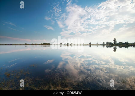 Il cielo blu con nuvole bianche si riflette nel lago Foto Stock