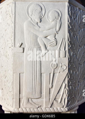 San Giuseppe Chiesa, Pickering, Regno Unito. Font scolpita da Eric Gill (1916) mostra Giuseppe e il bambino Gesù in un laboratorio di falegnameria Foto Stock