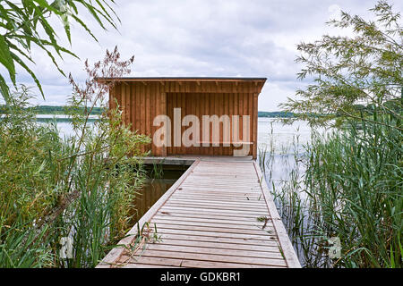 Birdwatch rifugio con bordo a bordo di rivestimento in legno, alla fine di un pontile in legno di uscire in acqua di un lago in Birkeroed, Foto Stock
