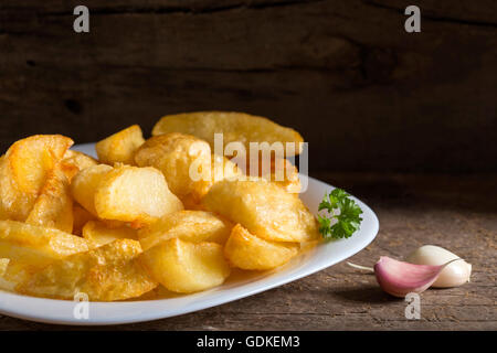 Porzione di le patate fritte fatte in casa (patate) sulla piastra bianca e legno sfondo rustico Foto Stock