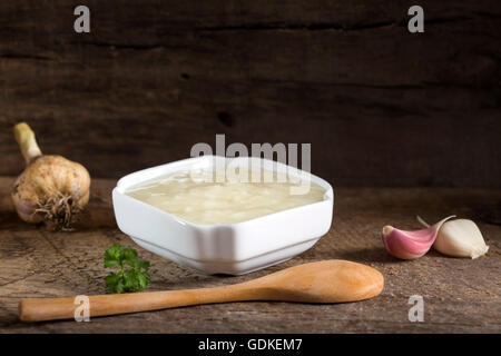 Aglio fresco salsa dip nella ciotola bianco su un vecchio rustico sfondo di legno Foto Stock