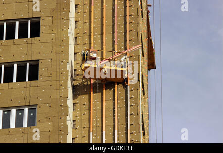 Costruzione sospesa culla giallo con lavoratori su la costruzione di un nuovo edificio alto Foto Stock
