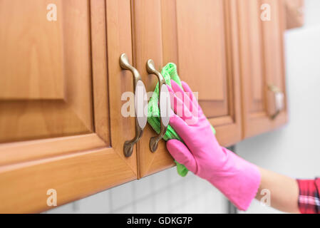 Donna guanti per pulire la polvere dall'armadietto porta. Close-up. Foto Stock