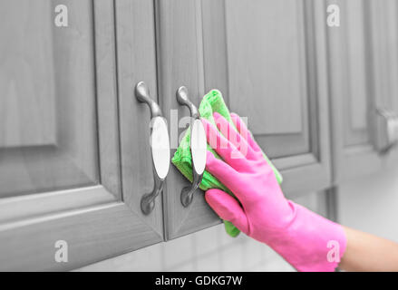 Donna guanti per pulire la polvere dall'armadietto porta. Close-up. Foto Stock