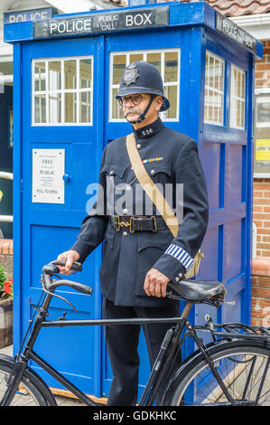 Woodhall Spa 1940 Festival - poliziotto vestito negli anni Quaranta era uniforme da un tradizionale telefono polizia box Foto Stock