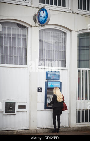 Wilmslow Barclays Bank bancomat ATM signora giovane ragazza donna che ha utilizzando un bancomat in street town center sola notte di sicuro de Foto Stock