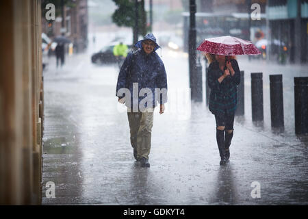 Heavy Rain nel centro della città di Manchester che piovono pour umido imbevuto di ammollo ombrello attraverso il rimbalzo del piano marciapiede spruzzi mi Foto Stock