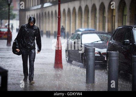 Heavy Rain nel centro della città di Manchester che piovono pour umido imbevuto di ammollo ombrello attraverso il rimbalzo del piano marciapiede spruzzi mi Foto Stock