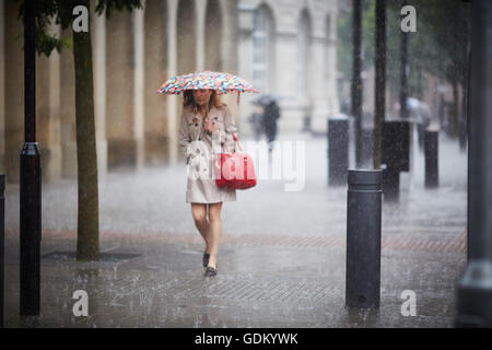 Heavy Rain nel centro della città di Manchester pioggia piovono pour umido imbevuto di ammollo ombrello attraverso il rimbalzo della pavimentazione del pavimento Foto Stock