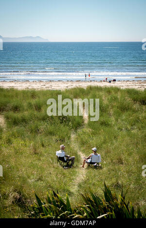 Coppia di anziani seduta su sedie a sdraio in duna di sabbia da un sentiero che conduce alla spiaggia. Ritiri sulla spiaggia. Inch Beach, County Kerry, Irlanda Foto Stock