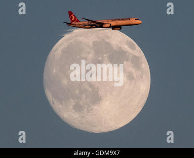 Un aeroplano vola attraverso un cielo privo di nuvole passato la luna prima di atterrare all'aeroporto di Frankfurt am Main, Germania, 18 luglio 2016. Foto: FRANK RUMPENHORST/dpa Foto Stock