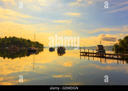 Su quello che è stato il giorno più caldo dell'estate, la si stabilirono le condizioni meteorologiche rendono per una splendida alba sulle calme acque del Loch Lomond, vicino a Glasgow, Scotland, Regno Unito Foto Stock