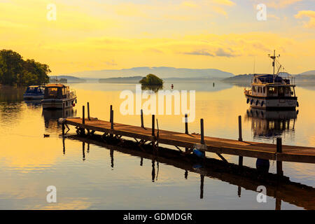 Su quello che è stato il giorno più caldo dell'estate, la si stabilirono le condizioni meteorologiche rendono per una splendida alba sulle calme acque del Loch Lomond, vicino a Glasgow, Scotland, Regno Unito Foto Stock