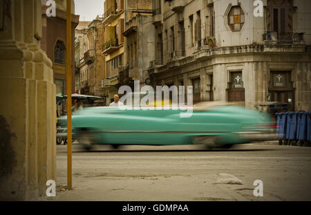 Luccicante classico americano convertibile in stile retrò che sfreccia attraverso edifici in decadenza a l'Avana Vecchia, Cuba. Auto al rallentatore Foto Stock