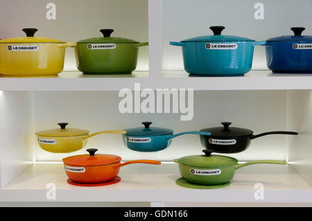 Colorato le Creuset cucina in ghisa smaltata su scaffale bianco in una boutique le Creuset Foto Stock